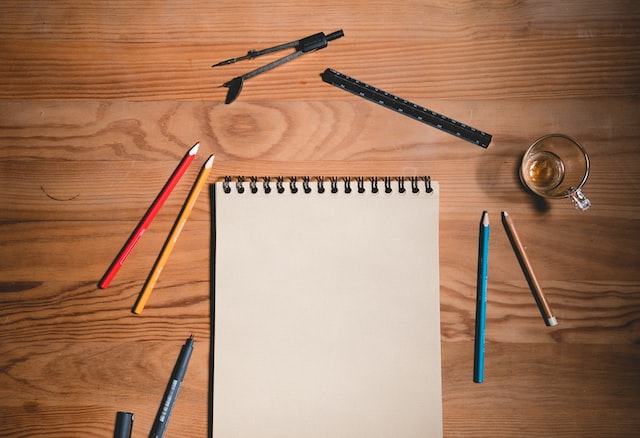 A notepad surrounded by pens on the table